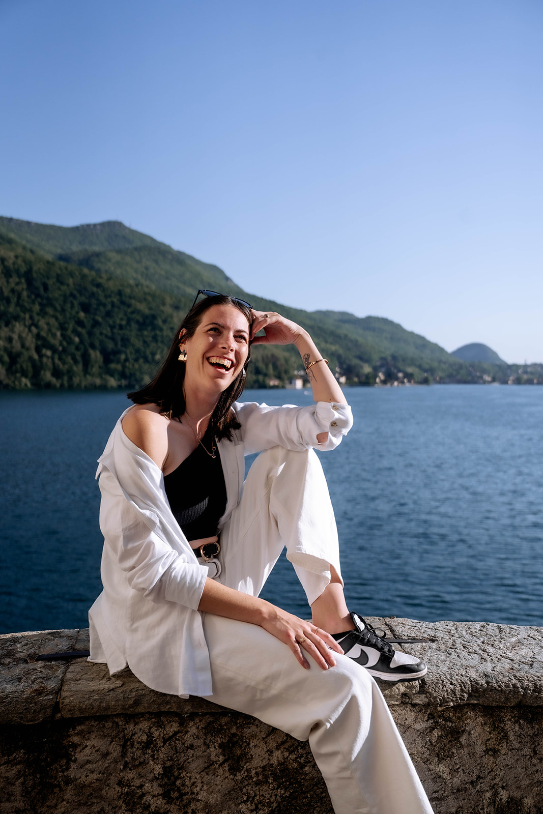 Marie Murer laechelnd auf einer Mauer am See